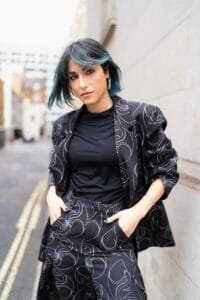 A woman with green hair standing next to a wall