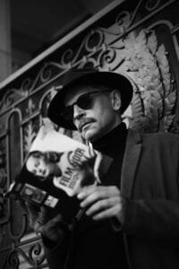 A man in a hat and sunglasses holding a cell phone