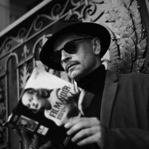 A man in a hat and sunglasses holding a cell phone