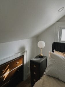 A bed sitting under a window next to a lamp