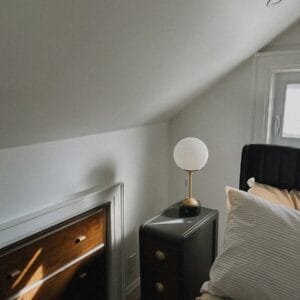 A bed sitting under a window next to a lamp